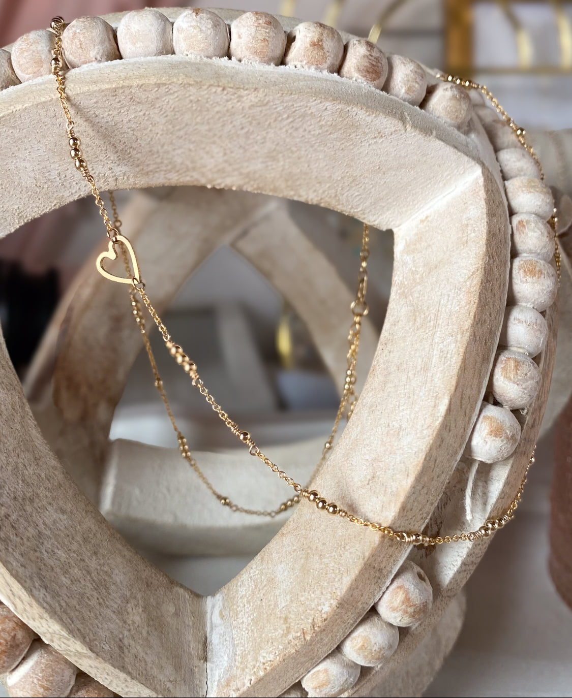 Gold necklace with a heart pendant on a decorative stone surface