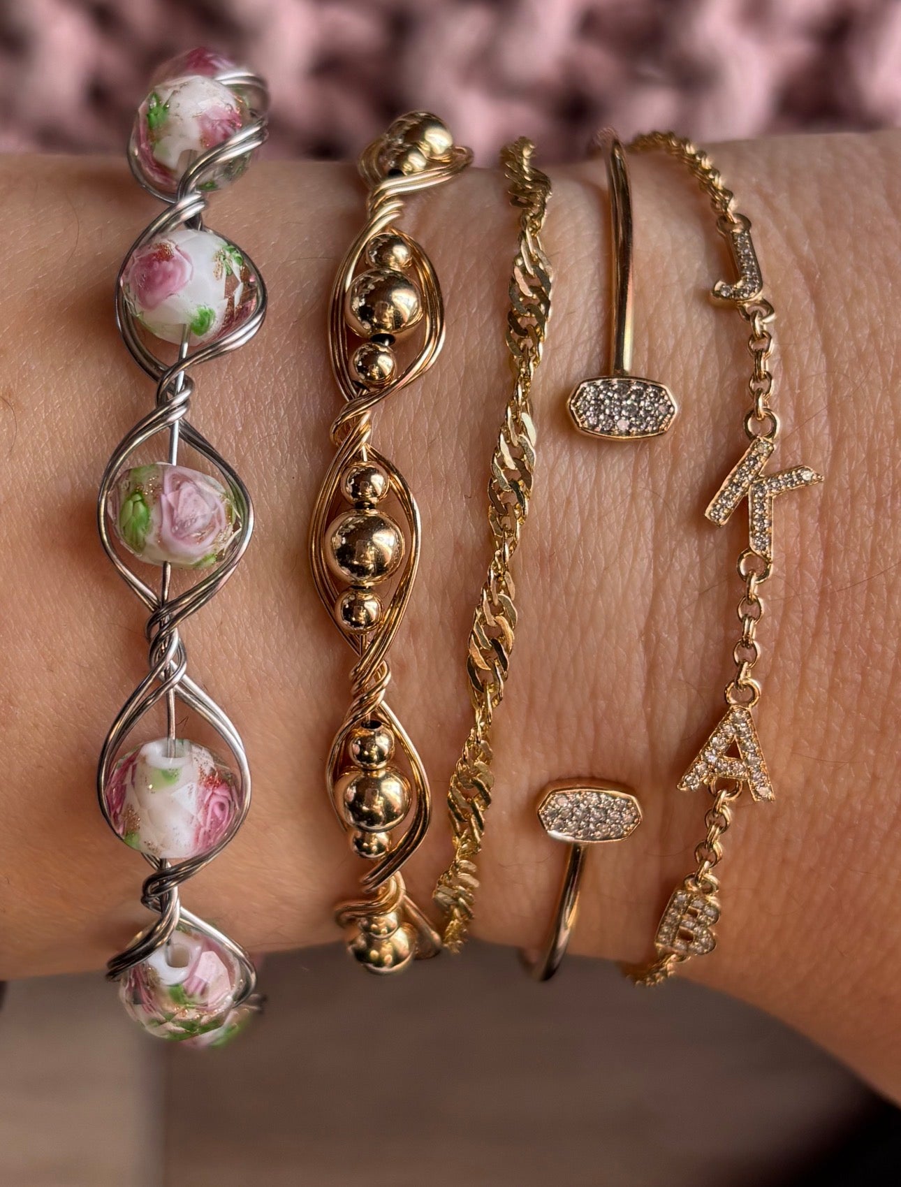 Collection of gold and silver bracelets on a wrist with a blurred background