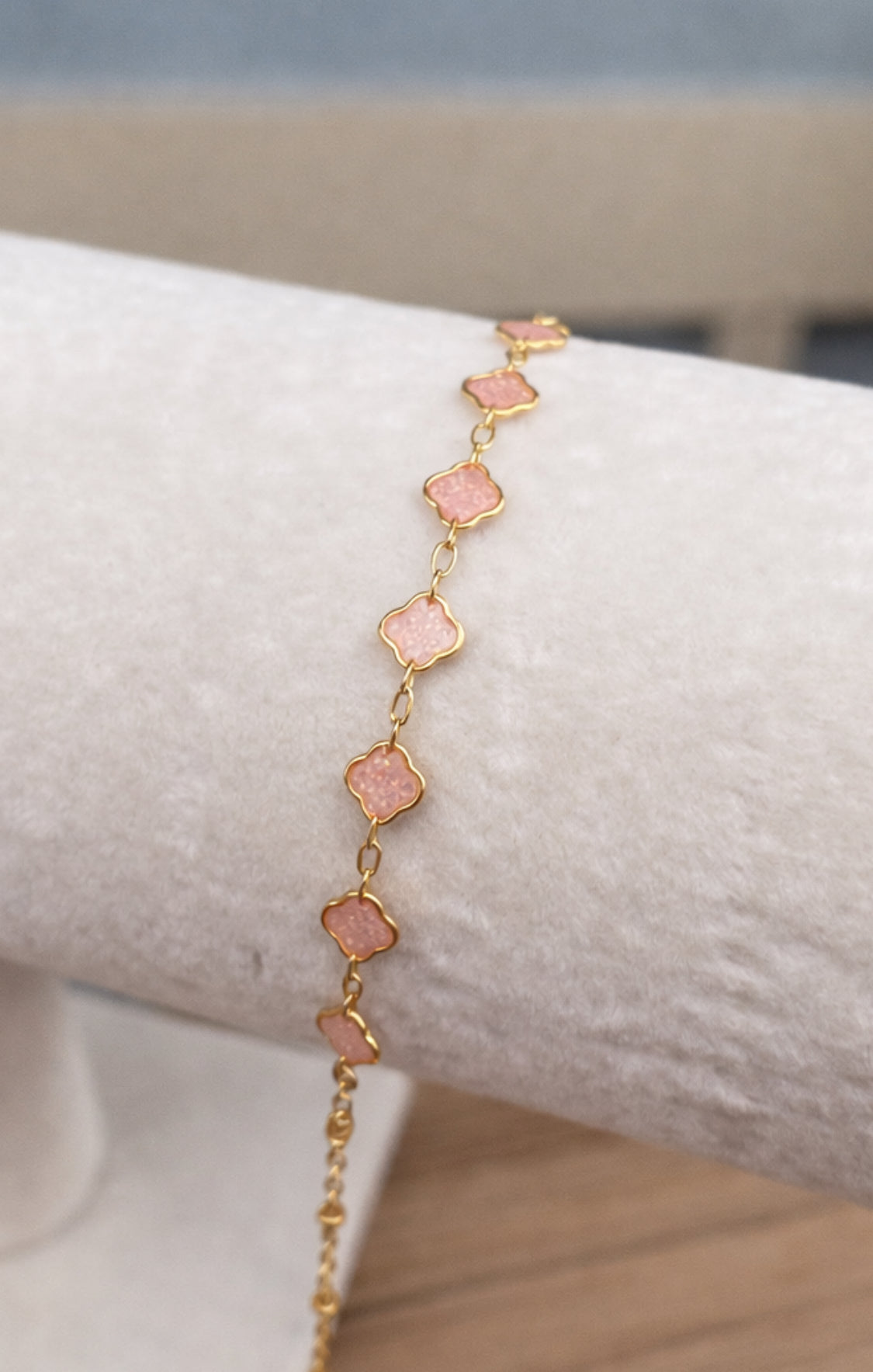 Gold bracelet with pink stones on a white surface