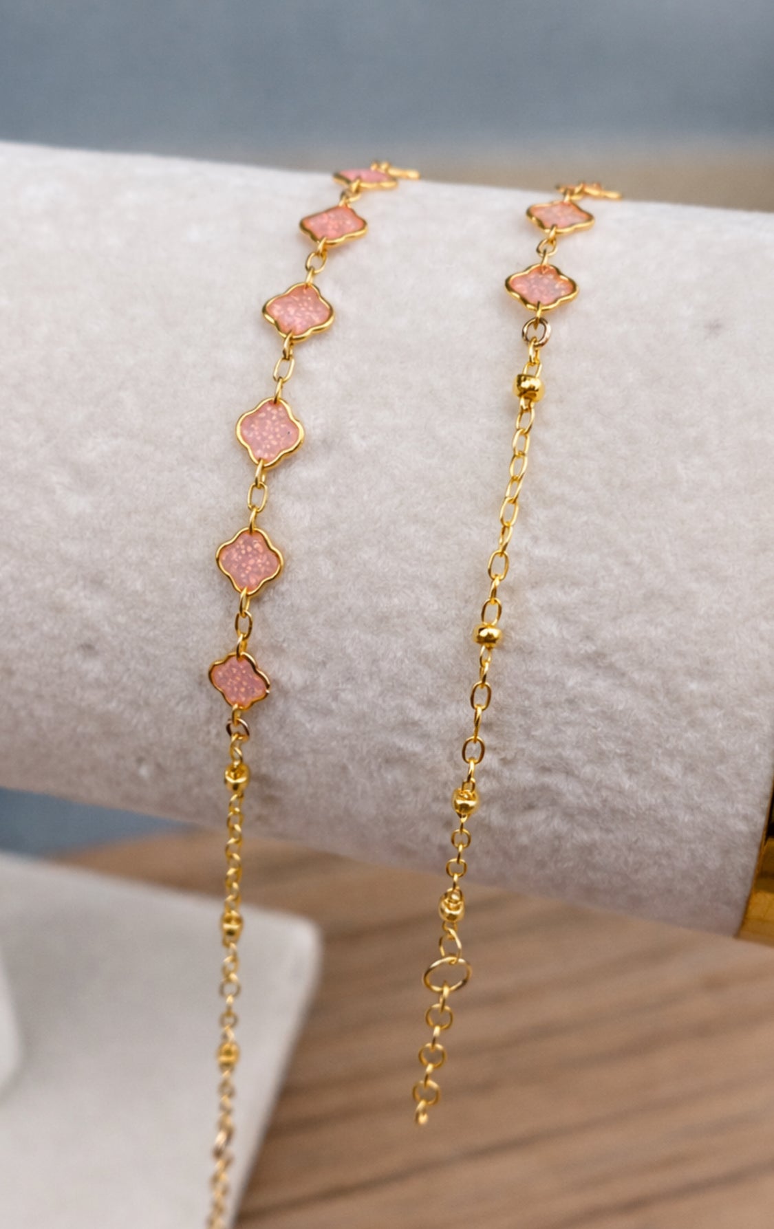 Gold bracelet with pink stones on a wrist against a neutral background