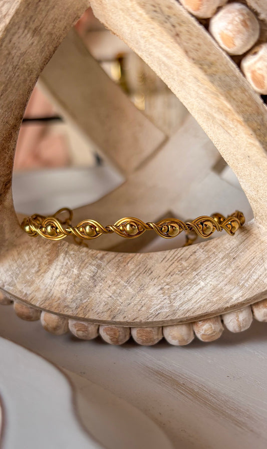 Gold bracelet on a wooden surface with a blurred background