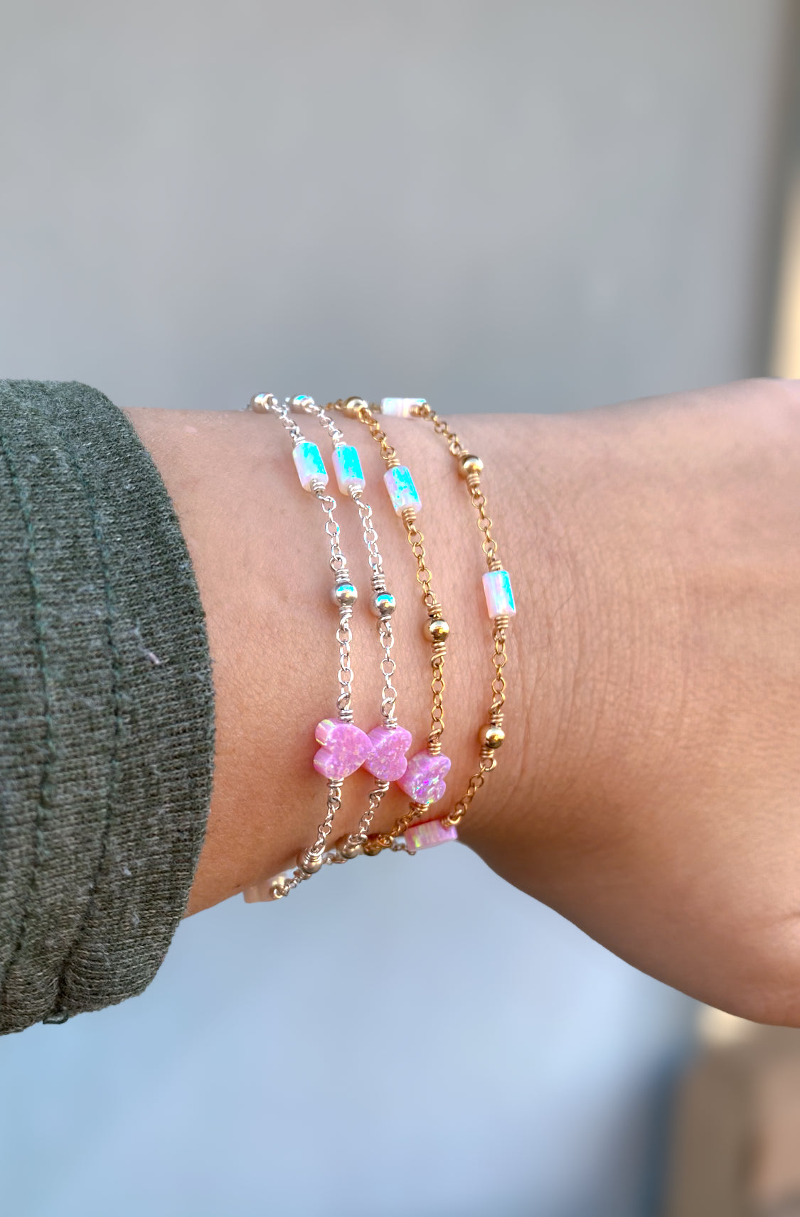 Handmade opal charm chain bracelet with iridescent gemstones, shown stacked on wrist for styling inspiration, available in gold filled and sterling silver