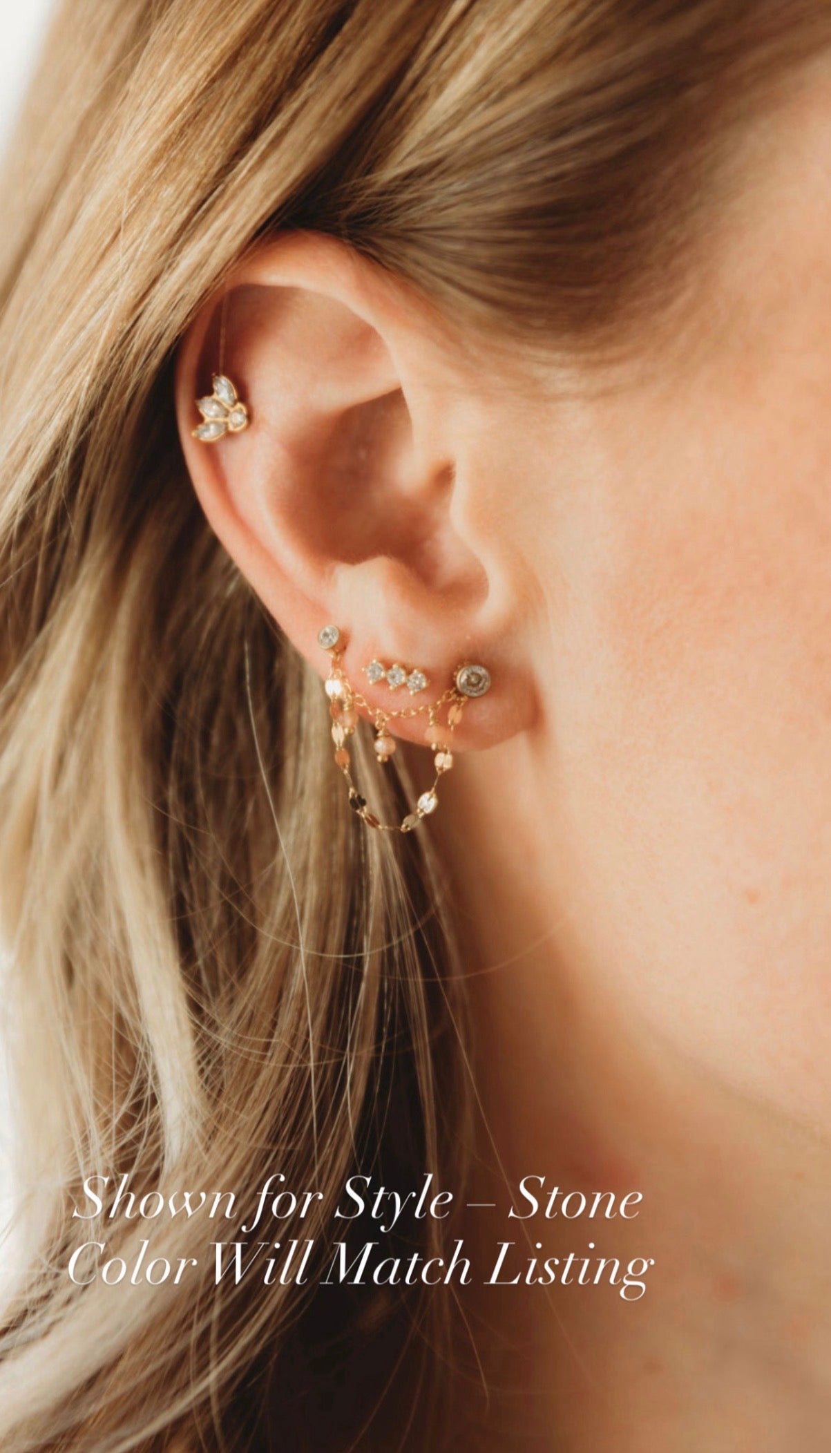 Gold filled and opal ear chain example Close-up of an ear with multiple gold earrings against a blurred background