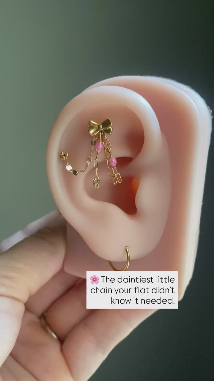 Handmade 14kt gold filled ear chain charm featuring a dainty heart dangle, pink glitter enamel starburst chain, and dapped leaf chain accents.
